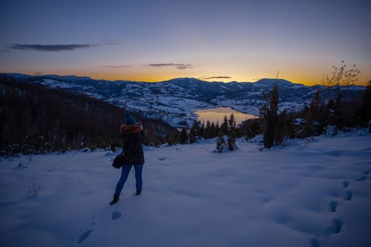 Photographers photographing winter lake mountain scene in sunset, alone in wilderness. Rovni, Valjevo, Serbia