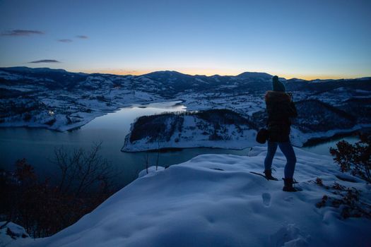 Photographers photographing winter lake mountain scene in sunset, alone in wilderness. Rovni, Valjevo, Serbia