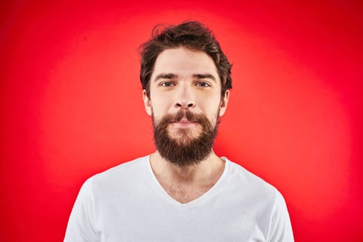 Bearded man fun emotions lifestyle cropped view white t-shirt red background. High quality photo