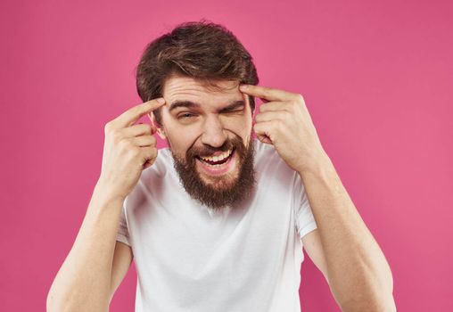 Happy man holds his hands near his face and laughs on a pink background. High quality photo