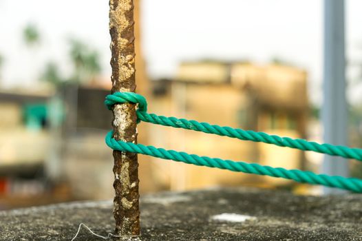 A rope is tied in a knot around a fence post, rope tied Hitch Knots on a rusty iron pole isolated from background.