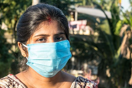 Smiling face wearing mask. Woman smiling wearing a face mask. Close up Front view of a happy Indian woman wearing a face mask smiling and looking at camera. Healthcare medicine background India.