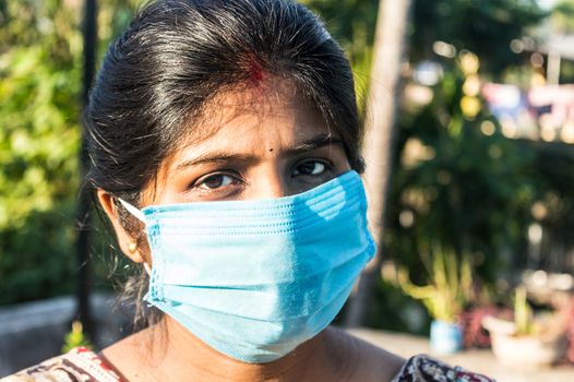 Smiling face wearing mask. Woman smiling wearing a face mask. Close up Front view of a happy Indian woman wearing a face mask smiling and looking at camera. Healthcare medicine background India.