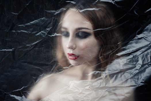 Young beauty sad woman trapped behind a plastic sheet as protection against COVID-19. Nicely fits for book cover