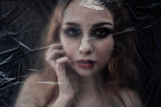 Young beauty sad woman trapped behind a plastic sheet as protection against COVID-19. Nicely fits for book cover