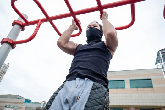 The guy is pushing up on the bars, in a black T-shirt and mask, in quarantine