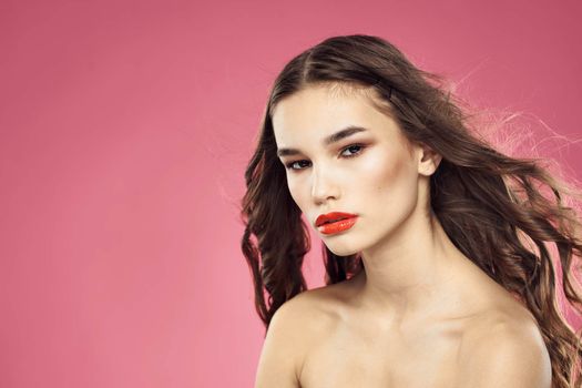 Beautiful woman with red lips on a pink background nude shoulders cropped view. High quality photo