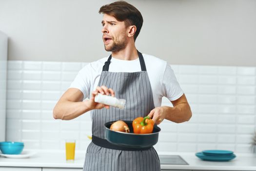 a chef in a gray apron with a pan in his hand fries vegetables