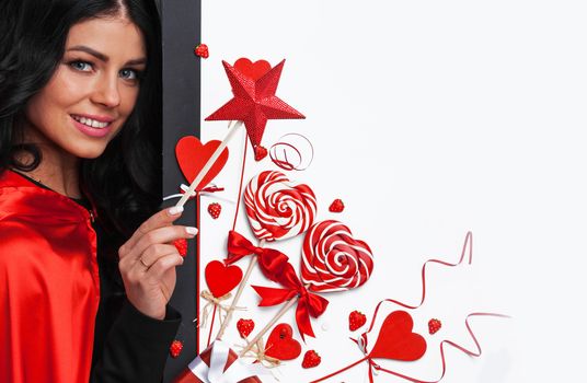 Woman with magic wand near Valentines day decoration and heart shaped lollipops isolated on white background