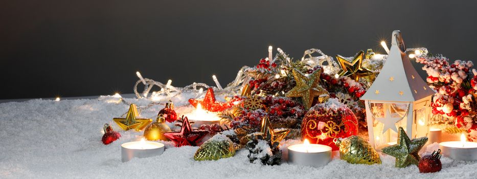 Christmas composition of lantern colorful ornaments balls stars candles and fir tree branches on snow