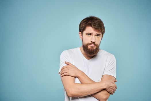 Man in white t-shirt lifestyle studio emotions facial expression blue isolated background. High quality photo