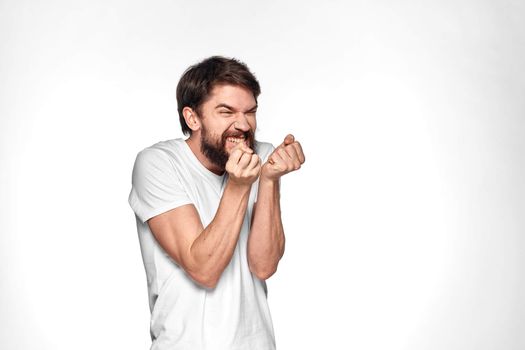 Bearded man in white t-shirt gesture with hands emotions light background. High quality photo