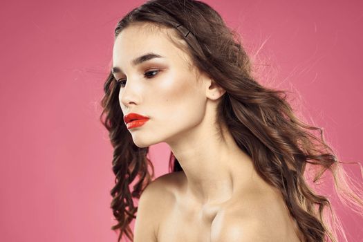 Beautiful woman with red lips on a pink background nude shoulders cropped view. High quality photo