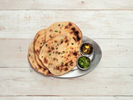 Fresh naan bread on white wooden background with copy space. Top view of several perfect naan flatbreads on metal tray