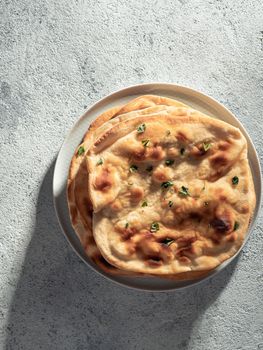 Fresh naan bread on gray cement background with copy space. Top view of several perfect naan flatbreads. Vertical