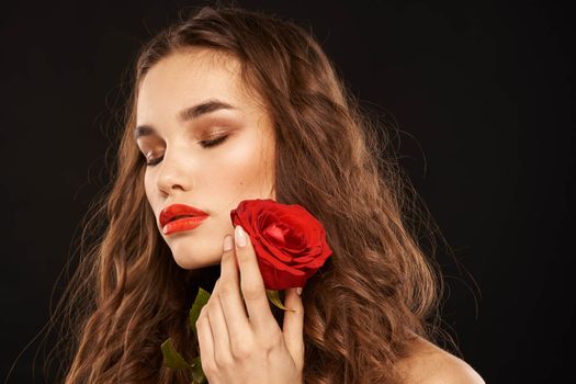 woman with a red rose on a dark background long hair makeup red lips. High quality photo