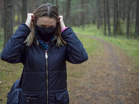 Beautiful european Women Wearing Protective Mask Outside Pretty young girl in medical black face mask in a forest. covid19 concept. modern reality. copy space. 2020, allergy. Autumn season. Copy space