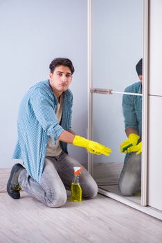 Young man cleaning mirror at home hotel