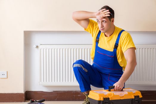 Young repairman contractor repairing heating panel 