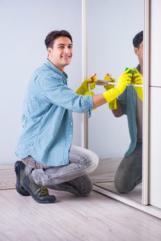 Young man cleaning mirror at home hotel