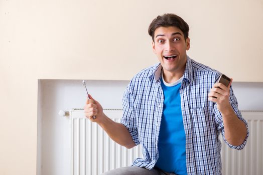 Young repairman contractor repairing heating panel 