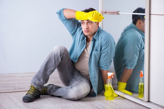 Young man cleaning mirror at home hotel