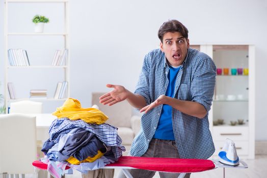 Young man husband doing clothing ironing at home