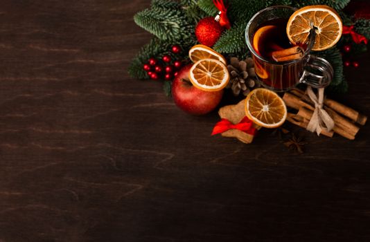 Mulled wine with cinnamon sticks orange fir tree branch and baubles Christmas composition over dark wooden background