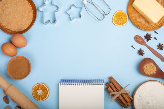 Christmas gingerbread cookies cooking background flat lay top view template with copy space for text. Baking utensils, spices and food ingredients on blue background