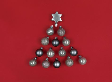 Christmas tree shape made with decor baubles on red paper.