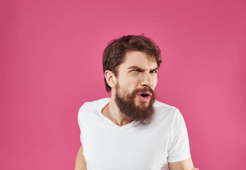 Angry man yells on pink background stress irritability model. High quality photo