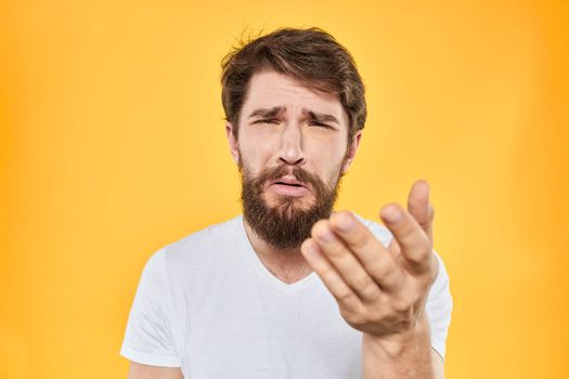 A man in a white t-shirt gestures with his hands studio lifestyle yellow background emotions. High quality photo