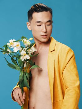 guy in a yellow coat asian appearance white flowers bouquet and side view. High quality photo