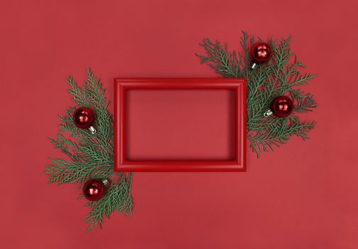 Red frame, tree branches and decor baubles. Christmas monochrome flatlay with copy space.