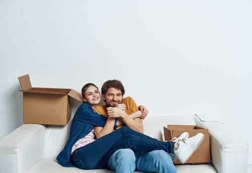 man and woman sitting on a white sofa in a room with boxes of things tools moving. High quality photo