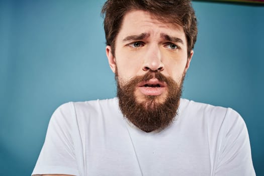 Man in white t-shirt lifestyle studio emotions facial expression blue isolated background. High quality photo