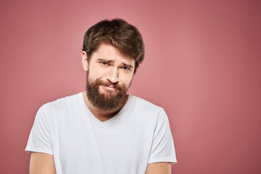 emotional man white t shirt sad facial expression pink background. High quality photo