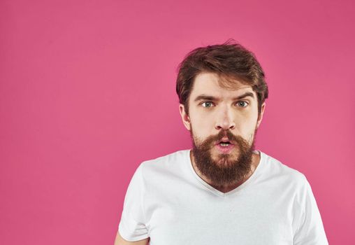 Emotional man gesturing with his hands on a pink background Copy Space. High quality photo
