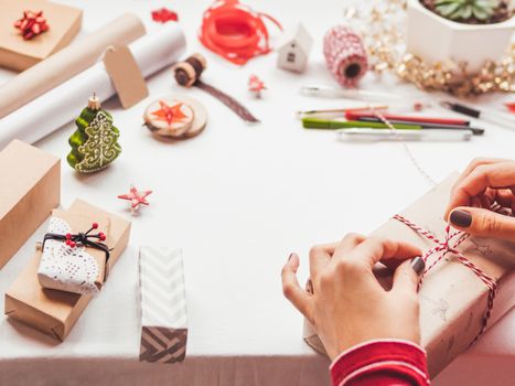 Table with Christmas decorations. Woman draws New Year symbols on craft paper and wraps presents. Flat lay with copy space.
