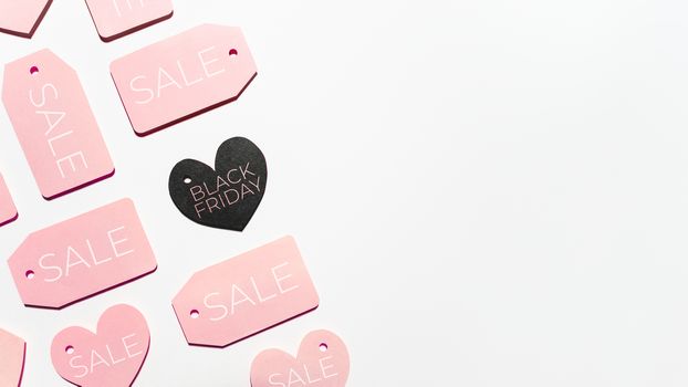 Top view on pattern of pink and black clothes tags in shape of heart on white background. Glamorous labels with copy space. Symbol of black Friday sale and shopping. Flat lay.