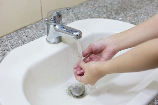 Washing hand on  sink with water.