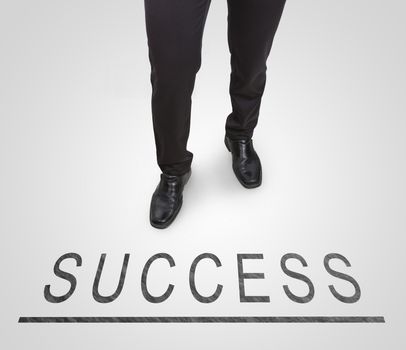 Businessman standing wearing court shoes on success line.