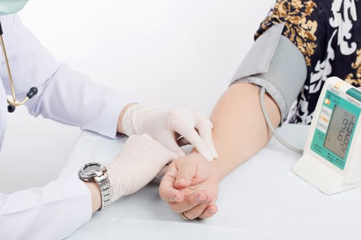 Doctor checking pulse of patient with stethoscope  on table isolated white background. 