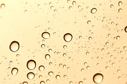 Gold water drop on glass mirror background.