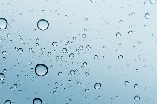 Water drop blue sky on glass mirror background.