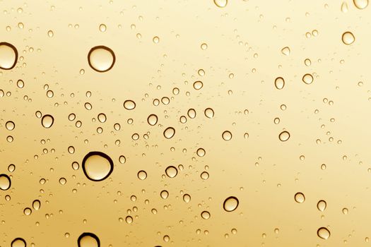 Gold water drop on glass mirror background.