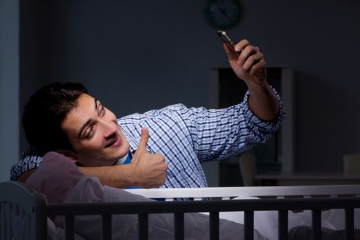 Happy dad looking after newborn baby at night
