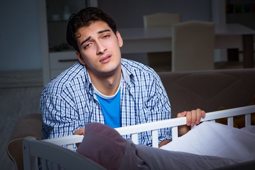 Young father dad sleeping while looking after newborn baby