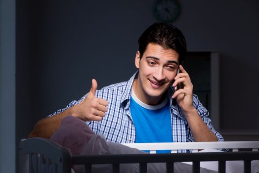 Happy dad looking after newborn baby at night