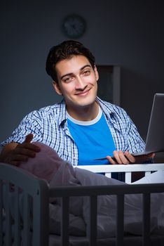 Young student doing homework and looking after newborn baby